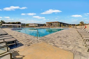 Ein Schwimmbad mit Liegestühlen und einem Gebäude im Hintergrund.