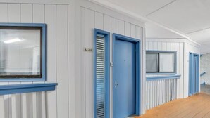 A corridor with blue-framed windows, a wooden floor, and a door labeled 'A-215'. - Modern Ocean Oasis - Private Beach • Pool • OceanViews (Hilton Head Island)