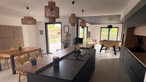A modern kitchen with a central island, wooden furniture, and pendant lighting. - Family villa with pool & summer kitchen  (Beaupuy)