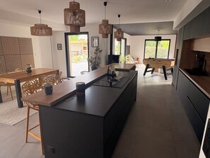 A modern kitchen with a central island, wooden furniture, and pendant lighting. - Family villa with pool & summer kitchen  (Beaupuy)