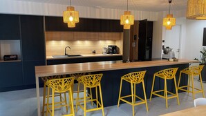 A modern kitchen with a central island, bar stools, and pendant lighting. - Family villa with pool & summer kitchen  (Beaupuy)