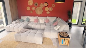 A modern living room with a sectional sofa, decorative wall art, and a small wooden side table. - Family villa with pool & summer kitchen  (Beaupuy)