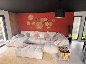 A modern living room with a sectional sofa, decorative wall art, and a small wooden side table. - Family villa with pool & summer kitchen  (Beaupuy)