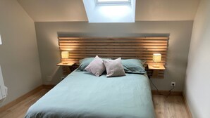 A bedroom with a bed, two bedside tables, a skylight, and a wooden headboard. - The swallow barn (Azé)