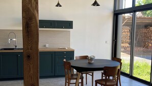 A modern kitchen with a dining table, chairs, and pendant lights. - The swallow barn (Azé)