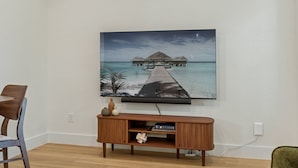 Una TV a schermo piatto montata su una parete sopra un mobile in legno con una scena di un oceano tropicale.
