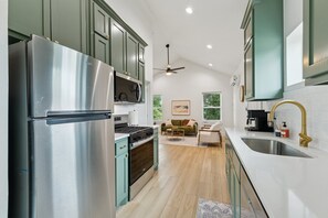 A modern kitchen with stainless steel appliances, a gas stove, and a ceiling fan. - Cozy and Modern 1-bedroom house in Edmond (Edmond)