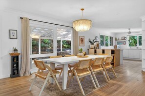 Eine moderne Küche mit Essbereich, großen Fenstern und einer Kristallleuchter.