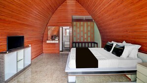 A bedroom with a bed, a TV, a wardrobe, and a bathroom visible through an open door.