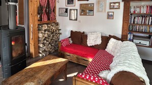 A cozy living room with a fireplace, a sofa, a wooden table, and a bookshelf. - Cosy village house (Jausiers)