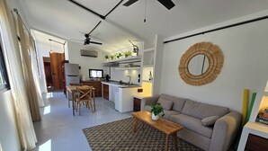 Un saló modern amb un sofà, una taula de centre i una zona de menjador amb cadires i una taula.
