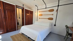 Un dormitori amb llit, armari de fusta i una decoració de taula de paddle surf penjada a la paret.