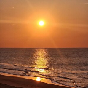 Un tramonto su una spiaggia con le onde che riflettono la luce del sole.