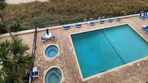 Ein Poolbereich mit einem großen rechteckigen Pool, kleineren kreisförmigen Pools und Liegestühlen.