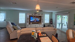 Ein Wohnzimmer mit einer Couch, einem Fernseher und einem Esstisch mit Spielkarten.