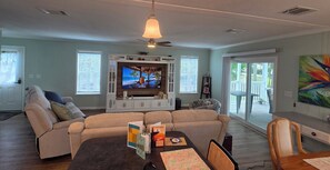 A living room with a sofa, TV, and a dining table with cards. - Your Stuart Oasis (Stuart)