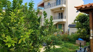 A multi-story residential building with balconies, surrounded by lush greenery and a garden. - Pavlos Apartment - Leontari Stay with Garden View (Leontario)