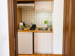 Een compact keukenhoekje met een inbouwkoelkast, een spoelbak en een klein aanrecht.