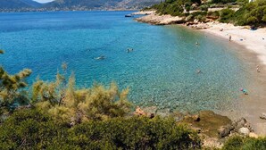 A coastal landscape with clear blue waters, a sandy beach, and rocky terrain. - Pavlos Apartment - Leontari Stay with Garden View (Leontario)