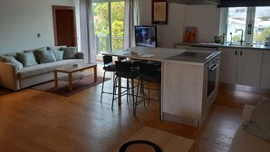Un ambiente compatto con divano, zona pranzo, angolo cottura e televisione.