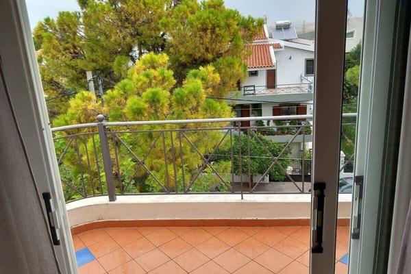View from the bedroom balcony over greenery and nearby houses.