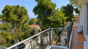 A balcony with a metal railing overlooking a residential area with trees and houses.