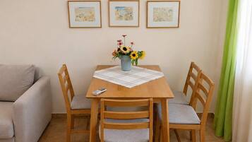 A dining area with a wooden table, four chairs, a vase with flowers, and a remote control on the table.