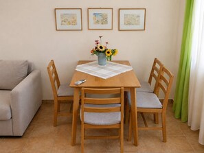 A dining area with a wooden table, four chairs, a vase with flowers, and a remote control on the table.
