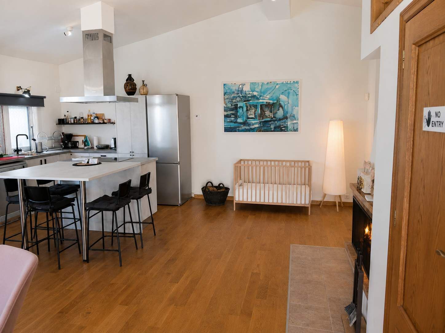 A modern kitchen with a central island, a dining area with chairs, a sofa, and a fireplace.