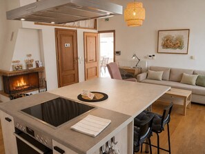A modern kitchen with a built-in oven, a central island with a digital scale, and a fireplace.