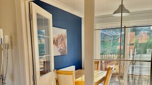 A room with a dining area, a painting on the wall, and a view through a glass door. - Detached 3-bedroom house with garage and garden. (Droitwich Spa)