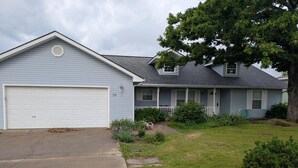 Ein Wohnhaus mit Garage, einer Veranda und einem gepflegten Rasen.