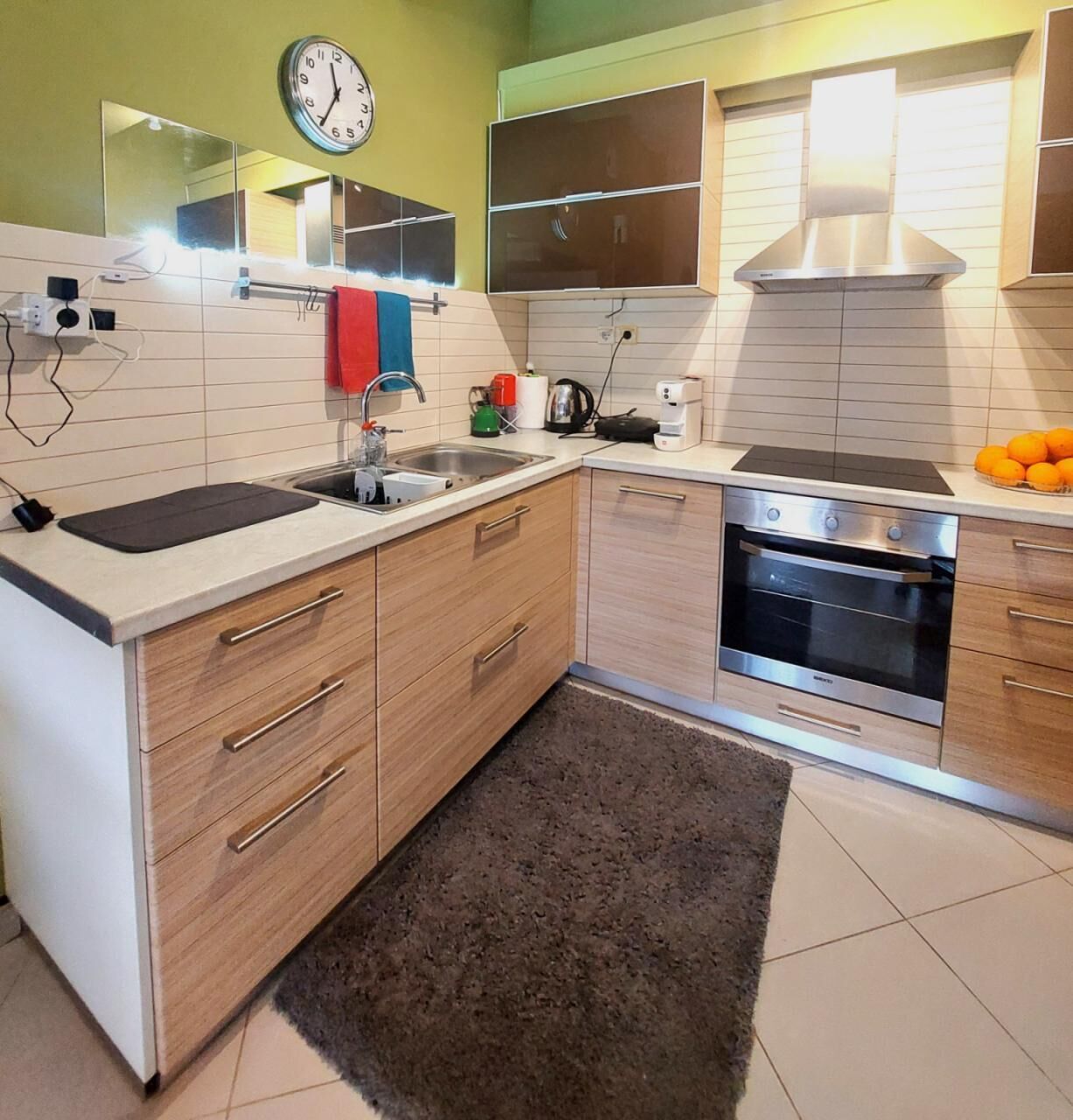 Una cocina moderna con horno empotrado, un fregadero y un reloj en la pared.