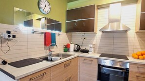 Een moderne keuken met een ingebouwde oven, een spoelbak en een klok aan de muur.