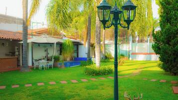A well-maintained garden with a lawn, a deer, and a patio area with outdoor furniture.