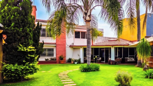 Una propiedad residencial con jardín cuidado, zona de estar exterior y piscina.