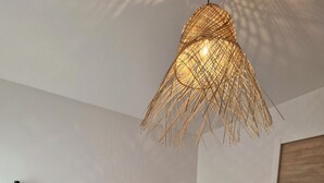A hotel room with a large bed, two wall-mounted lamps, and a woven ceiling light fixture. - Ty cocon, quiet family home - near Gulf of Morbihan (Colpo)