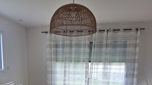 A living room with a sofa, a round coffee table, a decorative pineapple, a hanging light fixture, and sheer curtains. - Ty cocon, quiet family home - near Gulf of Morbihan (Colpo)