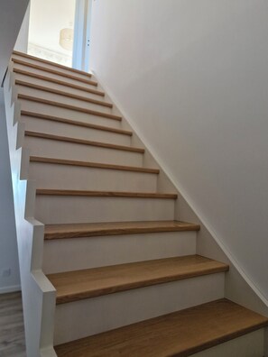 Una escalera con escalones de madera y paredes blancas.
