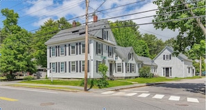 A two-story house with a front porch, located at the corner of a street. - Walk to town, 200yr-old 4BR house adjacent to Bowdoin campus! #2 (Brunswick)