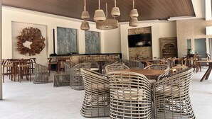 Un comedor espacioso con mobiliario de mimbre, techo de madera y obras de arte en las paredes.