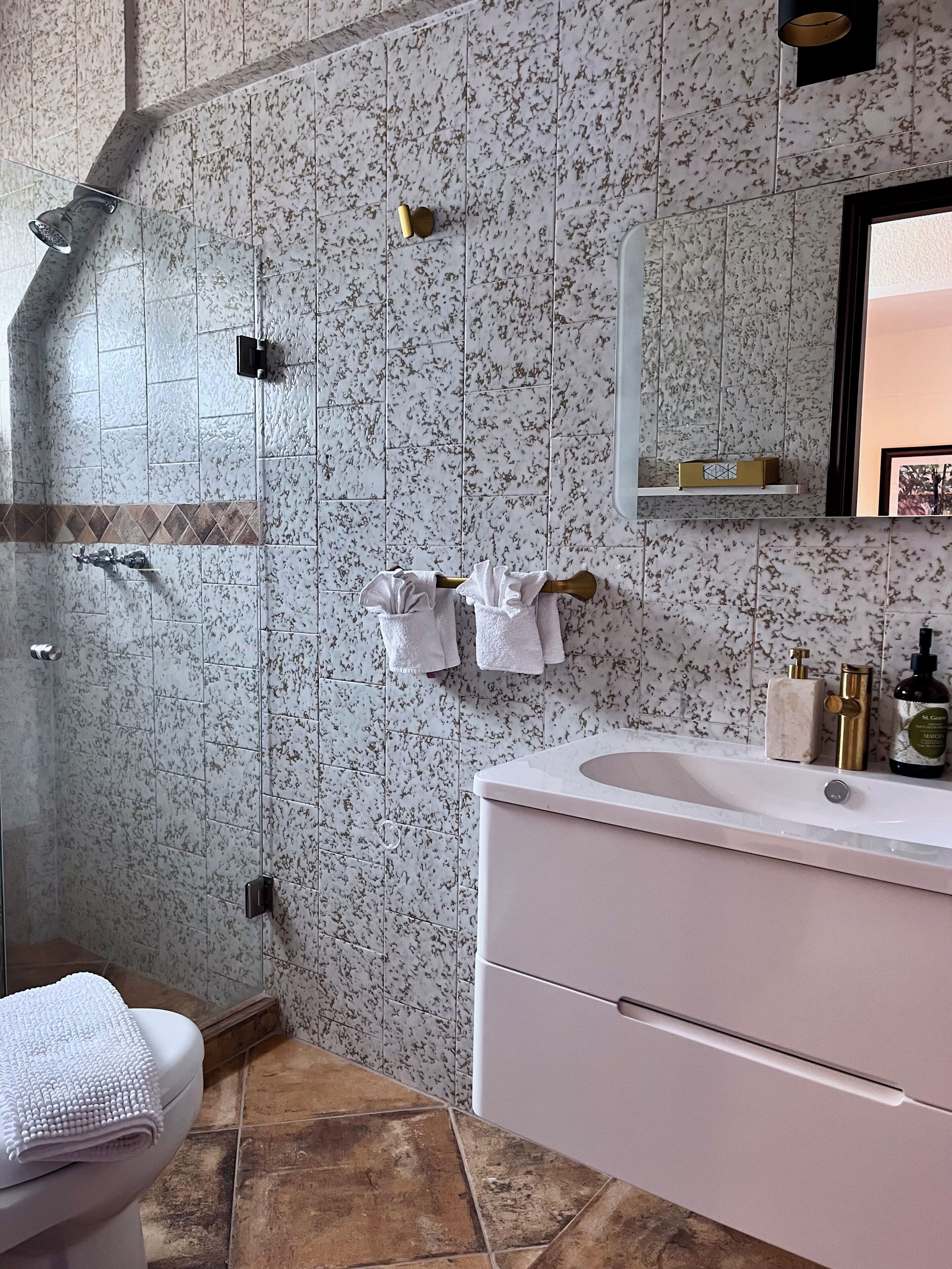 Ein Badezimmer mit Dusche, Toilette, Waschbecken und Spiegel.
