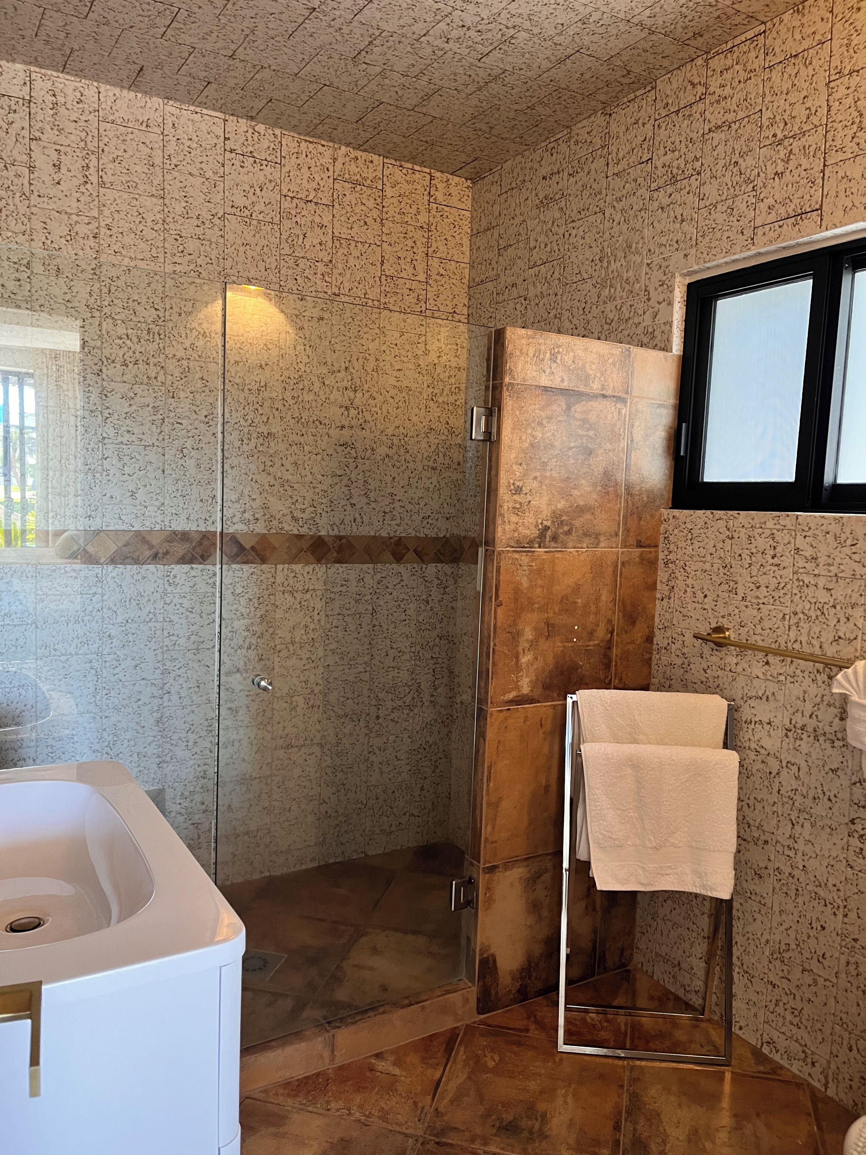 A bathroom with a glass shower enclosure, a white bathtub, and a towel rack.