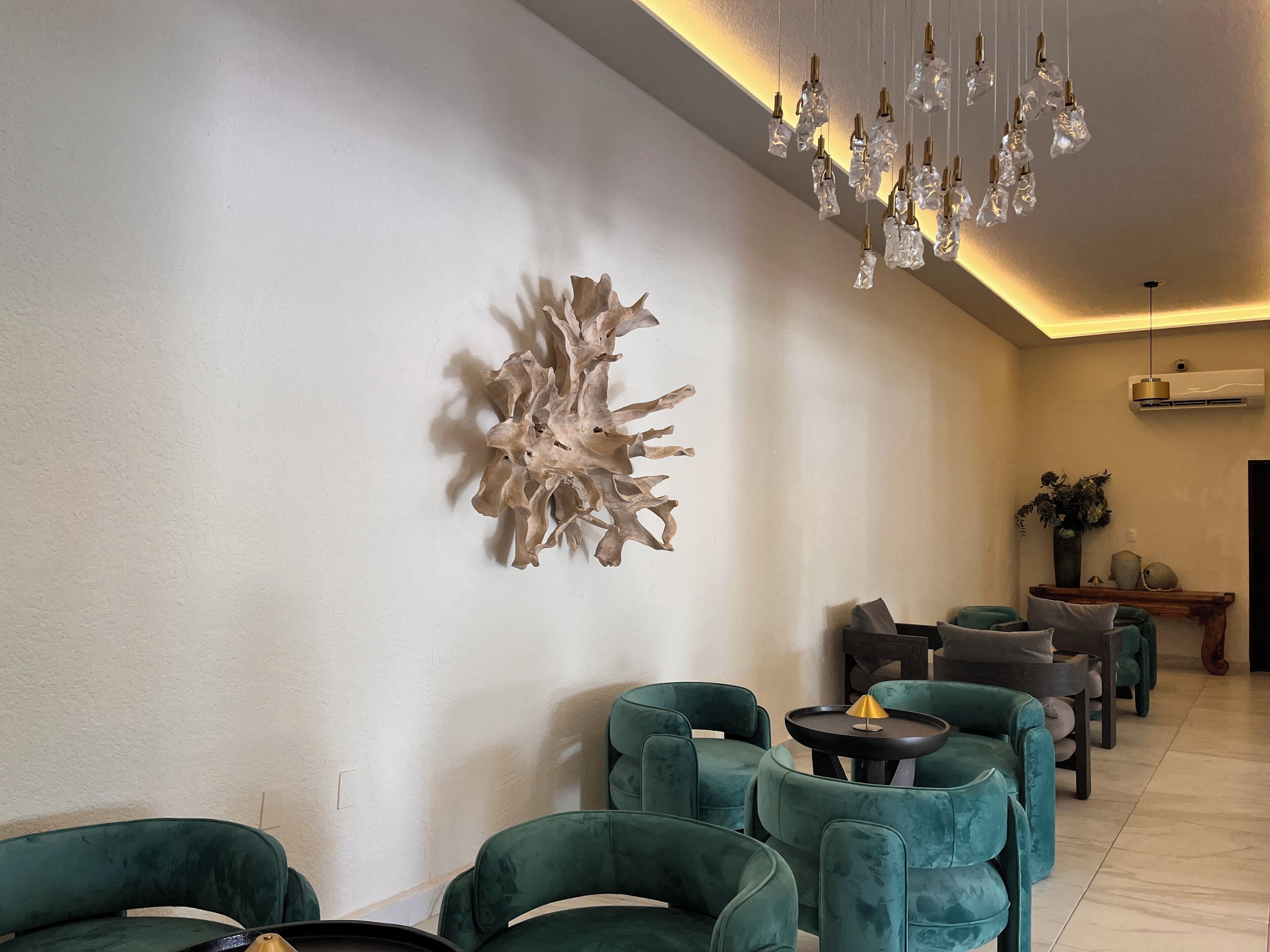 A modern interior with teal chairs, a unique wall sculpture, and a hanging light fixture.