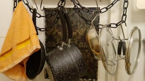 A kitchen with pots and pans hanging on a chain above a tiled backsplash. - Small Cosy Studio near City, Aldgate East (London)