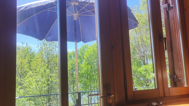 Een houten deur met uitzicht op een balkon en een grote parasol.