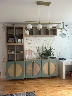 Een kamer met een houten boekenkast, een bureau en een muur met een bladmotief.