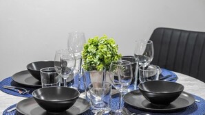 A dining table set with black bowls, glasses, and a small green plant centerpiece. - The Albany Hideout - Sleeps4  - QueenBed  - NFLX&Wifi (Edmonton)
