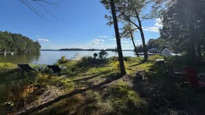 Kaunis paikka järven rannalla, jossa on laituri, tuoleja ja teltta.