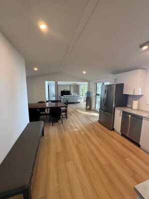 A modern kitchen with stainless steel appliances, a dining area with a table and chairs, and a large window providing natural light. - Lake Rosseau Escape, 3 Bedroom, New Reno, Hot Tub! (Minett)